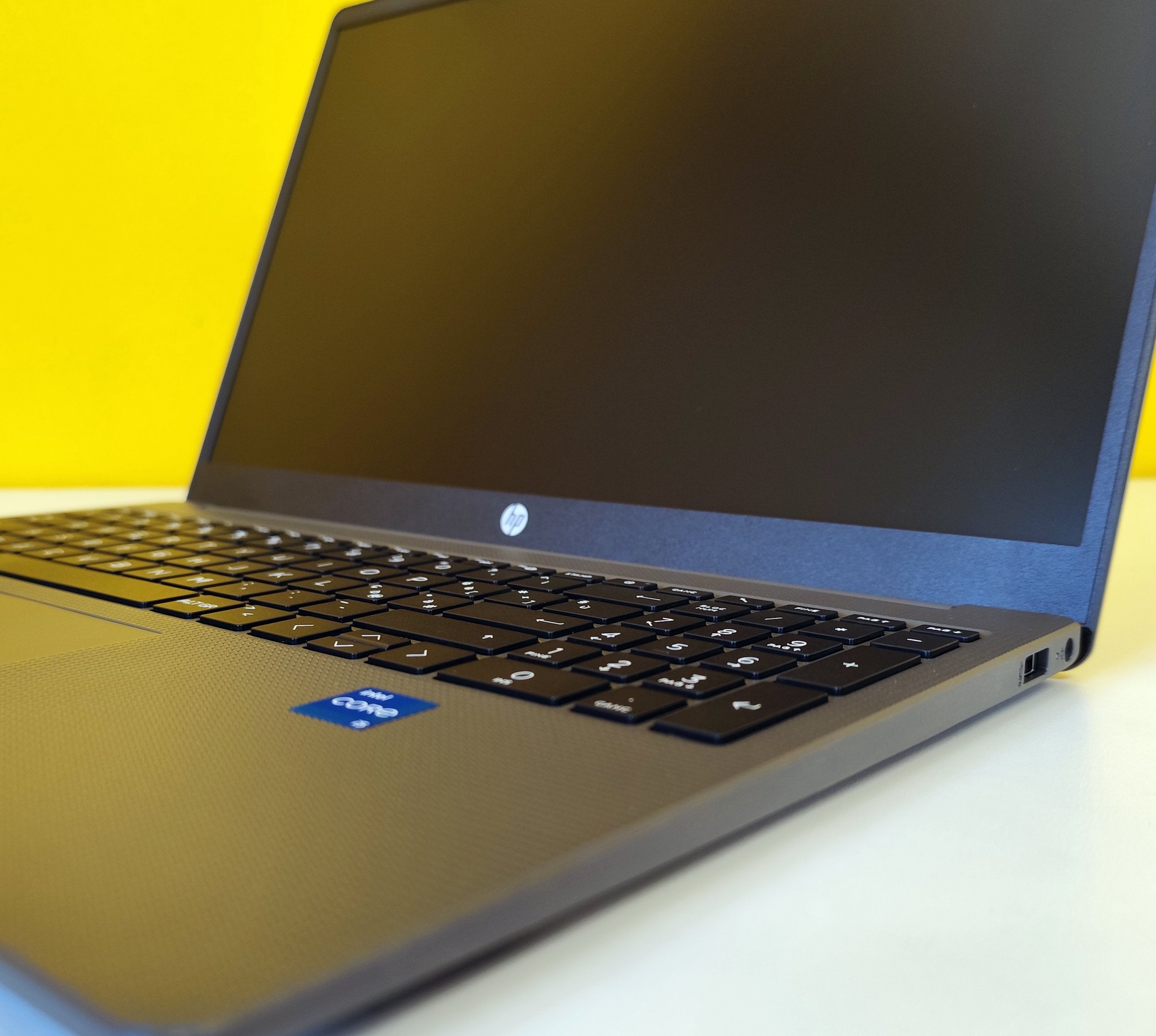 Notebook HP 250 G10 con adesivo Intel Core i5 visibile, tastiera estesa e design elegante su sfondo giallo.