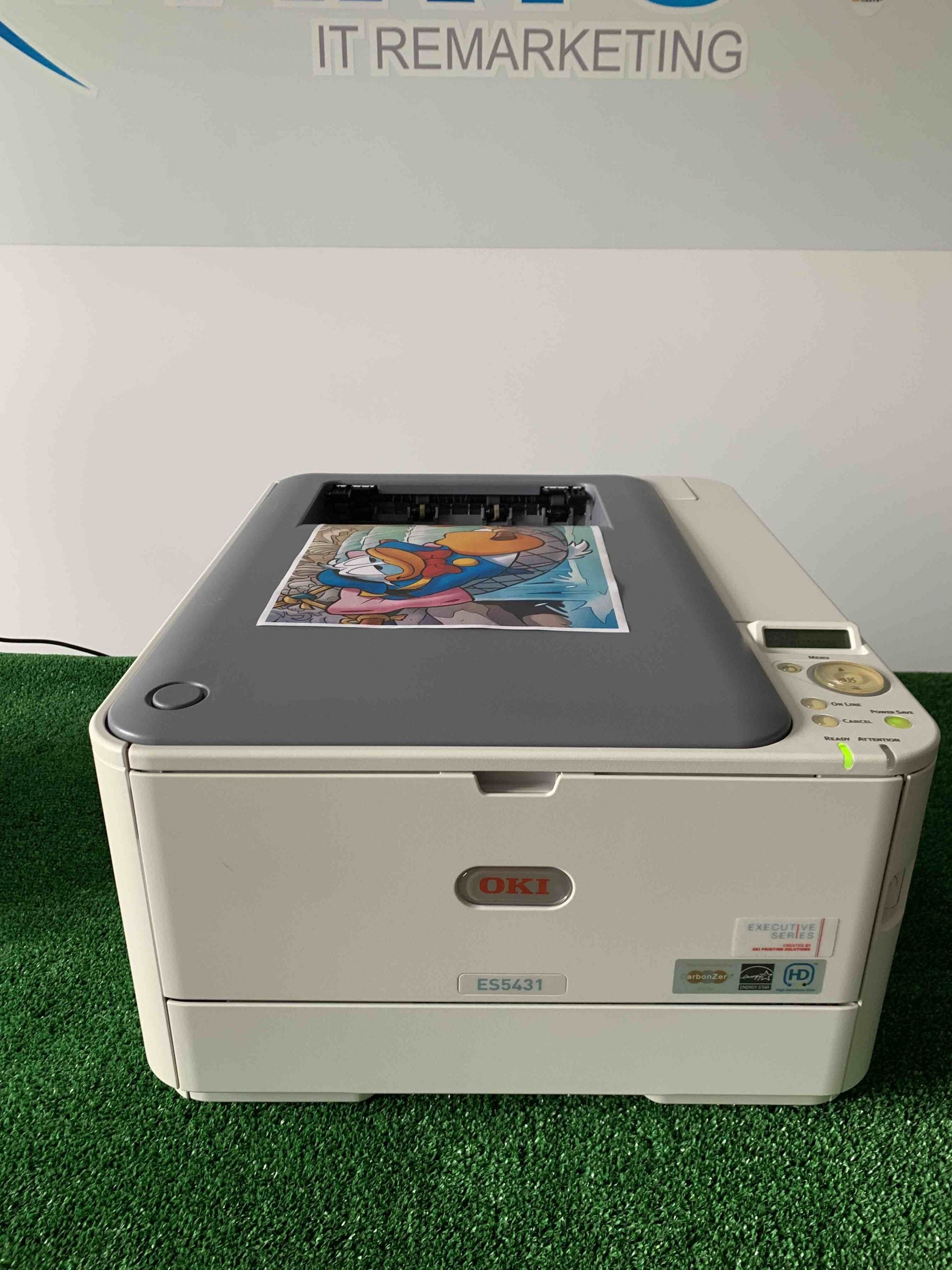 Stampante laser OKI ES5431 usata su tappeto verde, stampa a colori in primo piano.