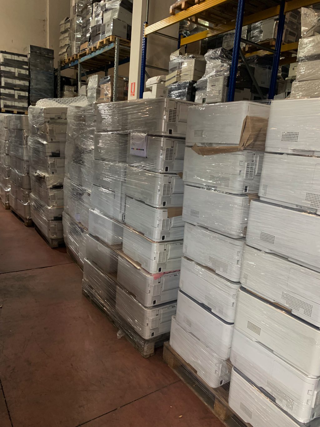 Magazzino con stampanti e multifunzioni laser ricondizionate impilate su pallet Messoanuovo.it